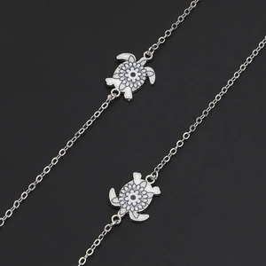 Silver turtle chain eyewear strap with detailed animal patterned charms on black background