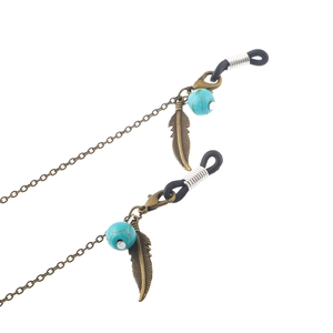 Chaîne lunettes bohème avec perles turquoise et pendentifs feuilles bronze sur fond blanc