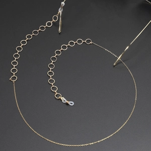 Chaîne de lunettes dorée avec anneaux et embouts silicone sur fond sombre chic