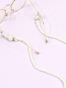 Detail of gold metal glasses chain with white pearls and anti-slip silicone loops