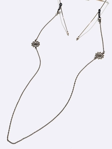 Detailed macro of vintage bronze eyeglass chain with intricate cutout daisy charms