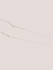 Close-up of gold glasses chain featuring delicate cross star charms and silicone loops