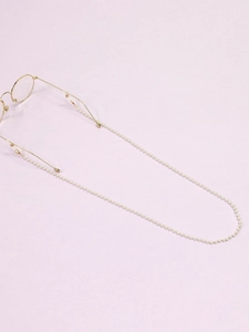 Detail of white handmade pearl glasses chain with gold metal hooks on purple background