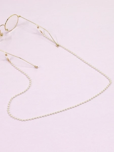 Close-up of a handmade white pearl glasses chain with gold metal connectors on eyewear