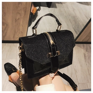 Detail der glitzernden schwarzen quadratischen Tasche mit Goldkette und Metallakzenten