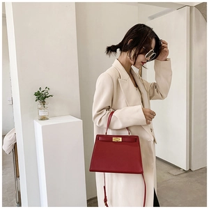 Détail du sac de mariée en cuir rouge avec fermoir doré et poignée supérieure unique