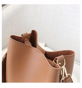 Detailed macro view of caramel brown leather bucket bag with gold hardware and grain texture