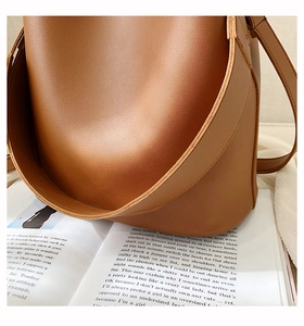 Close-up of caramel leather bucket bag texture and premium stitching details on magazine