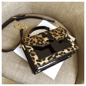 Detail der Leopardenmuster-Tasche mit Goldkette und schwarzer Lackleder-Textur