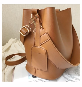 Detail of brown bucket bag with lychee texture leather and gold metal hardware