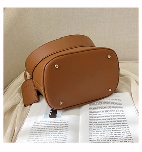 Detail view of brown leather bucket bag base featuring four gold protective metal rivets