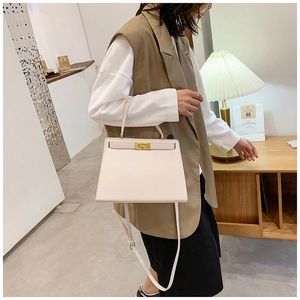 Détail du sac à main trapèze en cuir crème avec fermoir rotatif doré et bandoulière