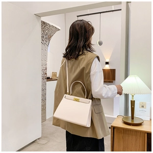 Détail du sac trapèze en cuir blanc cassé avec fermoir doré et bandoulière longue