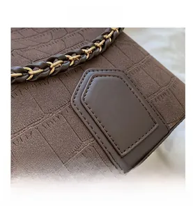 Macro detail of dark brown crocodile pattern texture and metallic woven chain strap