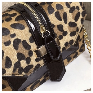 Nahaufnahme von Leoparden-Ponyhaar-Textur mit schwarzem Lackleder und Goldbeschlägen