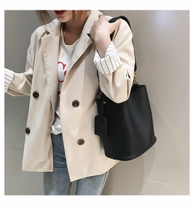 Detail of minimalist black leather bucket bag with golden hardware and square tag accessory