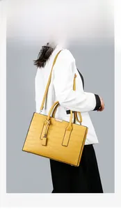Detailed close-up of yellow crocodile texture on vintage tote bag with metal hardware