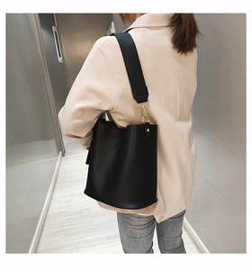 Detail of black matte leather bucket bag with wide strap and gold metal hardware