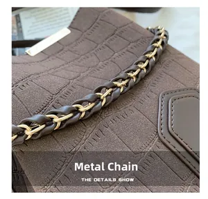 Detail of crocodile embossed leather and elegant gold metal chain strap on bucket bag