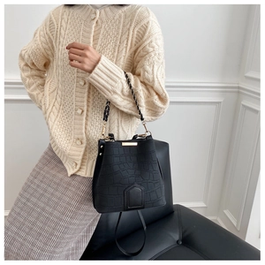 Detail of black crocodile texture bucket bag with gold chain strap on stylish model