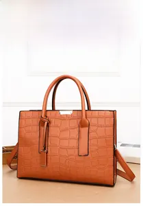Detail of orange crocodile embossed leather handbag with metal buckle and top handles
