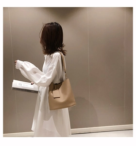 Detailed view of khaki leather bucket bag with metal feet and elegant strap details