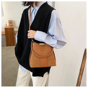 Detail of brown faux-crocodile bucket bag with metal chain handle and vintage texture