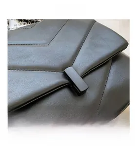 Close-up of black chevron stitched leather flap and matte rectangular clasp on shoulder bag