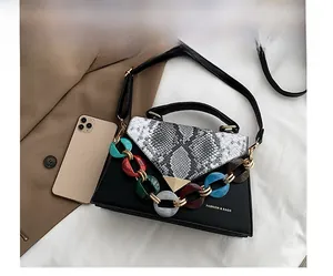 Close-up of snakeskin pattern flap bag with gold lock and colorful acrylic chain