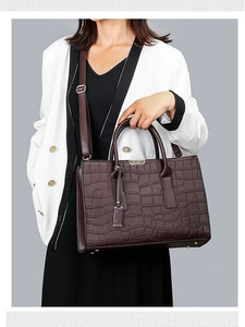 Close-up of deep brown crocodile embossed tote bag with gold hardware and shoulder strap