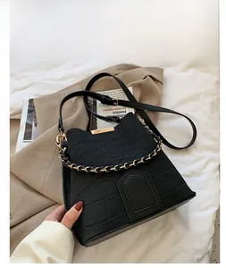 Close-up of black crocodile pattern bucket bag with metal chain handle and leather strap