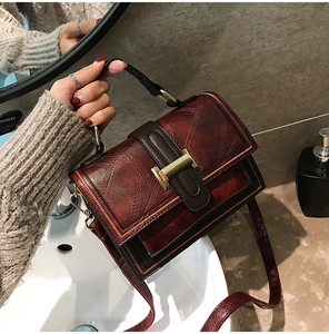 Macro detail of wine red leather texture and vintage gold metal clasp on crossbody bag