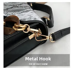 Detail of golden lobster clasp and brown marble acrylic chain on snake pattern bag