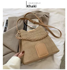 Detail of khaki bucket bag with crocodile texture and stylish woven handle on grey blazer