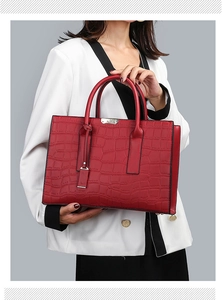 Close-up of red crocodile pattern handbag with dual handles and elegant black edge finishing