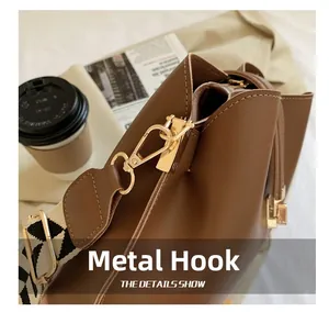 Close-up of golden metal hooks and woven strap on a brown leather shoulder bag