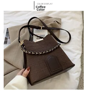 Detail of coffee brown bucket bag with crocodile pattern and metal chain handle