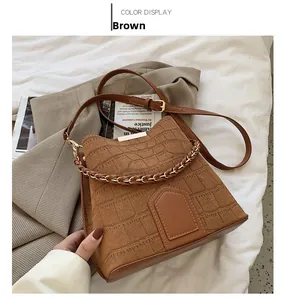 Detailed macro view of the brown crocodile pattern bucket bag with metal chain handle