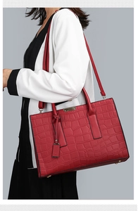 Detail of red crocodile pattern handbag with gold hardware and PU leather texture