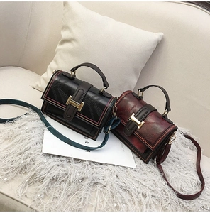 Close-up of retro square crossbody bag in oil wax leather with decorative belt detail