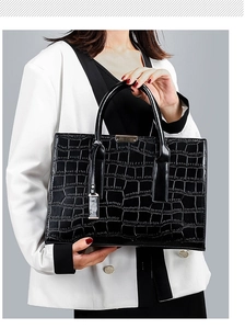 Detail shot of black crocodile embossed faux leather handbag with metallic hardware accents