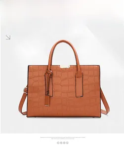 Detail view of brown crocodile embossed tote bag with metal hardware and leather texture