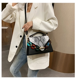 Detail of snake print crossbody bag with colorful chunky chain on white blazer
