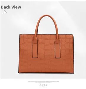 Detailed view of back side of tan crocodile embossed tote bag with sturdy handles