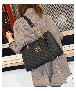 Détail du sac cabas matelassé noir avec chaîne dorée porté par un mannequin de dos