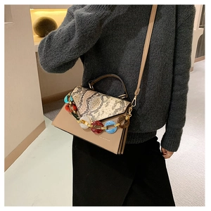 Detail of crossbody bag featuring snakeskin texture flap and colorful resin chain links