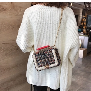 Gros plan d'un sac bandoulière en tweed avec perles et chaîne dorée sur pull blanc