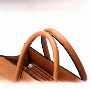 Detail of caramel leather handbag with fine embossed texture and gold metal zipper