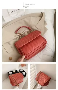 Detail of watermelon red crossbody bag featuring V-shaped quilting and gold chain strap