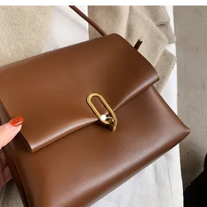 Close-up of a brown leather crossbody bag featuring a premium golden U-shaped metal lock